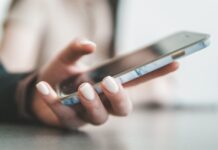 Como Organizar as Finanças Pessoais com Apps: O Método que Funciona Mao feminina segurando smartphone com capa de marmore